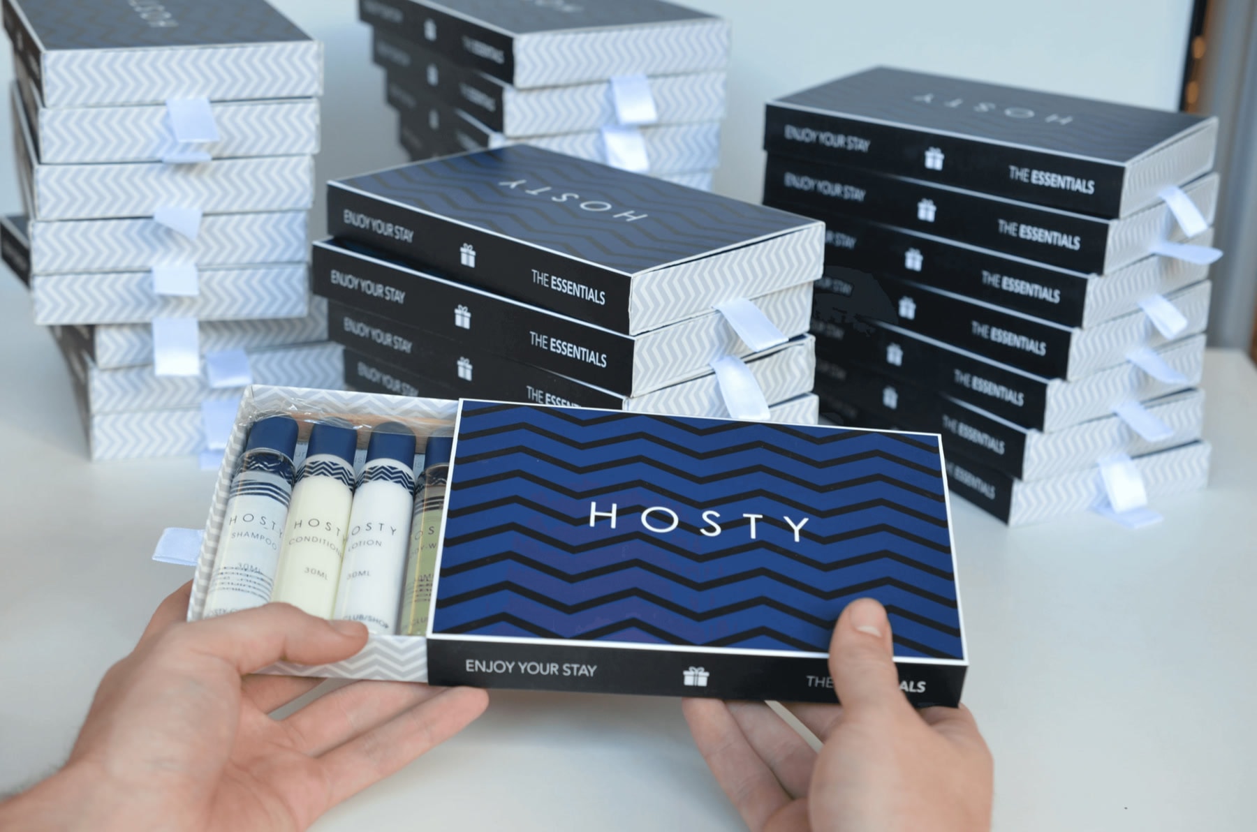Hands holding an open blue Hosty box in front of stacks from the first production run